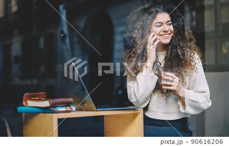 Cheerful hipster girl with laptop computer enjoying friendly mobile talking Cheerful hipster girl with laptop computer enjoying friendly mobile talking 90616206