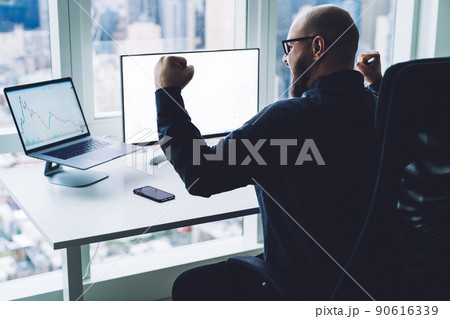 Excited broker celebrating victory while watching multimedia gadgets in office Excited broker celebrating victory while watching multimedia gadgets in office 90616339