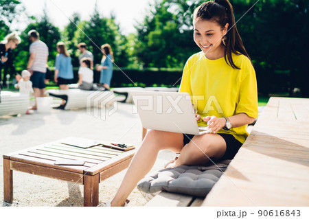 Young woman spending day cheerfully with laptop in park 90616843