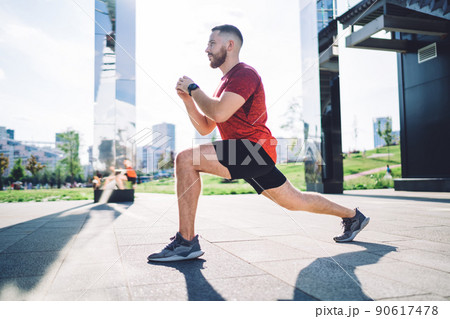 Focused sportsman stretching legs on street 90617478