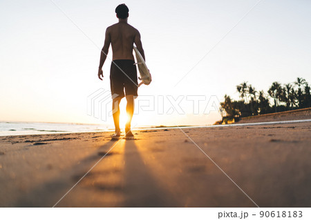 Sportive male surfer walking during summer vacations at Punalu'u Beach in Hawaii Sportive male surfer walking during summer vacations at Punalu'u Beach in Hawaii 90618183