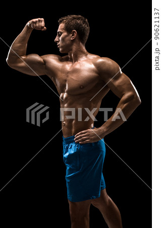 Muscular and fit young bodybuilder fitness male model posing over black background. 90621137