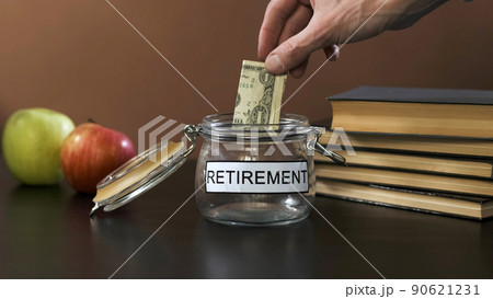 Man Putting Banknote into a Glass with Inscription Retirement, Increasing Savings. Investment and Personal Finance Management Concept 90621231