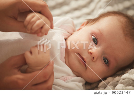 Face of cute little baby girl with beautiful big grey eyes lying on bed in white bodysuit 90623447