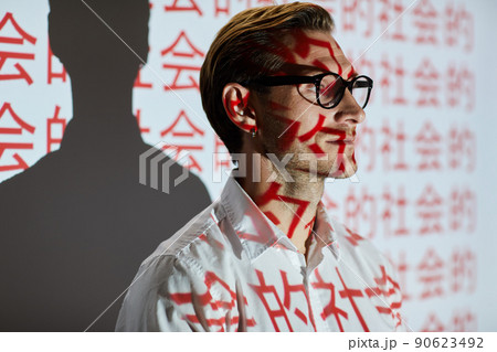 Confident young man with stubble standing by projection screen with hieroglyphs and resenting startup project to Chinese audience Confident young man with stubble standing by projection screen with hieroglyphs and resenting startup project to Chinese audience 90623492