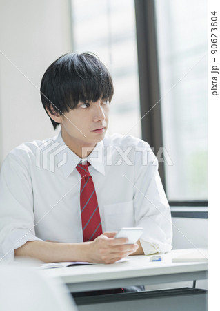 教室でスマートフォンを見る男性高校生 90623804