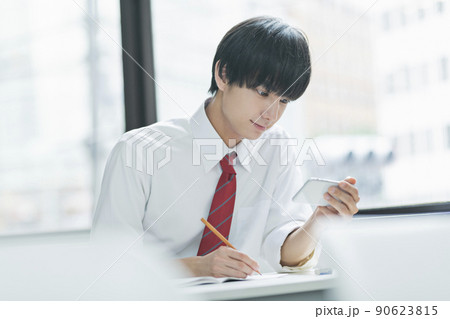 教室でスマートフォンを見る男性高校生 90623815