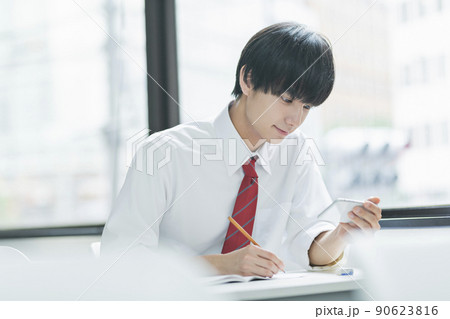 教室でスマートフォンを見る男性高校生 90623816