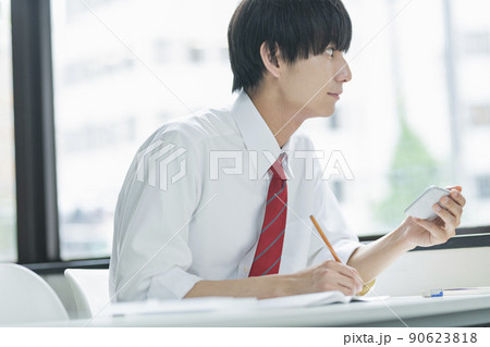 教室でスマートフォンを見る男性高校生 90623818