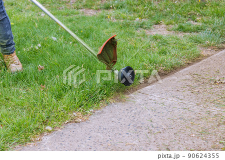The process of cutting the lawn with cordless grass trimmer edger The process of cutting the lawn with cordless grass trimmer edger 90624355