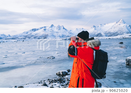 Lonely traveler with binocular on frozen coastline 90625020