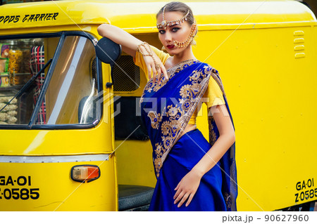 portrait indian beautiful Caucasian woman in traditional blue dress.hindu model with golden kundan jewelry set bindi earrings and nose ring piercing nath fashion photoshoot on srilankan street market portrait indian beautiful Caucasian woman in traditional blue dress.hindu model with golden kundan jewelry set bindi earrings and nose ring piercing nath fashion photoshoot on srilankan street market 90627960