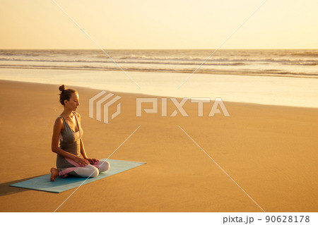 Silhouette of young woman in a stylish suit for yogi jumpsuit doing yoga on the beach in pose copy space 90628178