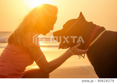 Blonde smiling young woman hugging her Cane Corso dog on the beach Blonde smiling young woman hugging her Cane Corso dog on the beach 90628279