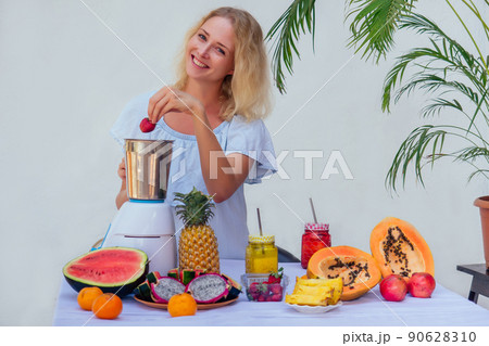Woman with perfect skin juicing making coctaile with juice machine in home kitchen. Healthy detox vegan diet with vegetable extractor to extract nutrients for smoothie drink.tropical asian vacation 90628310