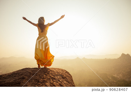 Woman inyellow silk long train dress in MAatanga hills in Hampi karnataka India 90628407