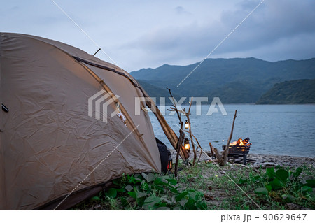 野営キャンプ ソロテント 無骨キャンプ 後ろ姿 海コピースペース ランプ 灯り 夕暮れ 夜キャンプ 90629647