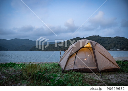 野営キャンプ ソロテント 無骨キャンプ 後ろ姿 海コピースペース ランプ 灯り 夕暮れ 夜キャンプ 90629682