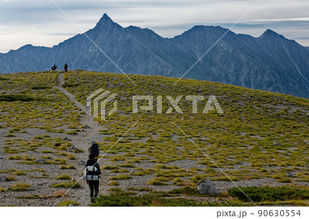 北アルプス・双六岳山頂平原を行く登山者と槍ヶ岳 90630554