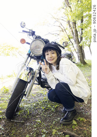 バイク女子イメージ　バイクと並んでポーズをとる若い女性 90632426