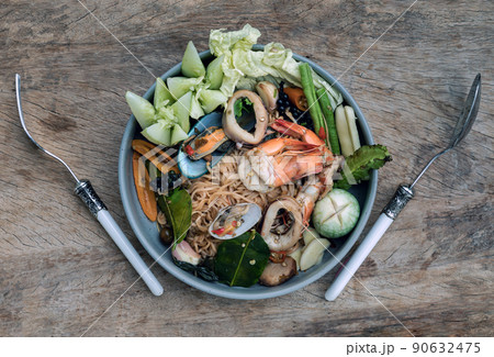 Spicy Stir Fried seafood Instant Noodles with herbs with various spices served with vegetables in ceramic plate. Spicy Stir Fried seafood Instant Noodles with herbs with various spices served with vegetables in ceramic plate. 90632475