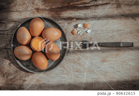 Composition of Broken fresh chicken egg (Hen egg) put at the middle of the fresh eggs with brown eggshell and Black antique silver fork on rustic old wooden table. Composition of Broken fresh chicken egg (Hen egg) put at the middle of the fresh eggs with brown eggshell and Black antique silver fork on rustic old wooden table. 90632615