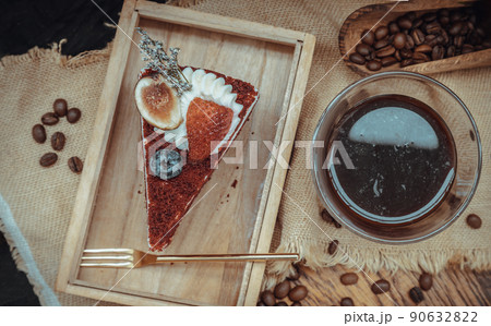 Piece of Red velvet cake serve with Espresso coffee in transparent glass on Wooden cutting board. 90632822