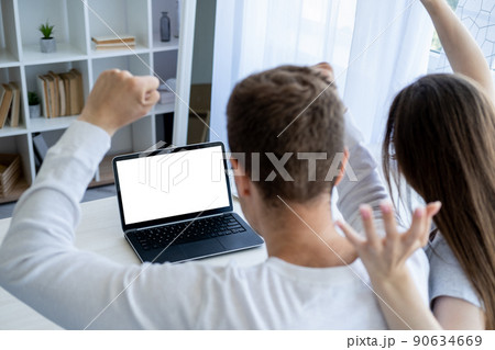 Winner excitement. Happy couple. Computer mockup. Cheerful unrecognizable man and woman looking laptop with blank screen hands up in light room interior. Winner excitement. Happy couple. Computer mockup. Cheerful unrecognizable man and woman looking laptop with blank screen hands up in light room interior. 90634669