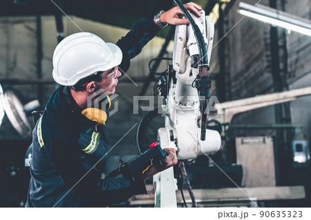 Young factory worker working with adept robotic arm Young factory worker working with adept robotic arm 90635323