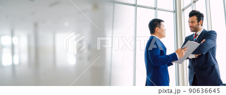 Two business people talk project strategy at office in widen view 90636645