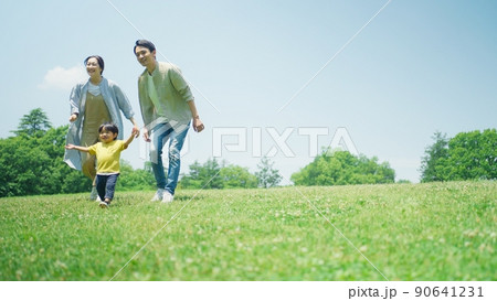 緑の丘で遊びまわる家族 90641231