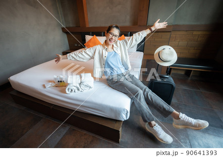 Happiness Asian tourist sitting on bed in hotel bedroom after check in. Conceptual of travel and accommodation. Happiness Asian tourist sitting on bed in hotel bedroom after check in. Conceptual of travel and accommodation. 90641393