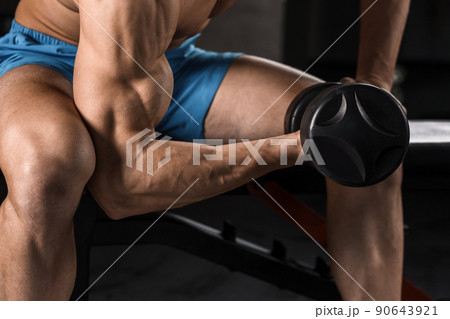 Very power athletic guy bodybuilder execute exercise with dumbbells at dark gym 90643921