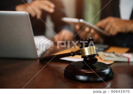 Justice and law concept.Male judge team in a courtroom the gavel, working with digital tablet computer on wood table. 90643970