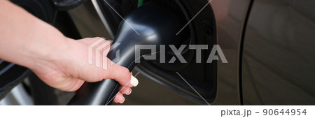 Woman put fuel nozzle on petrol station to refuel automobile with diesel Woman put fuel nozzle on petrol station to refuel automobile with diesel 90644954