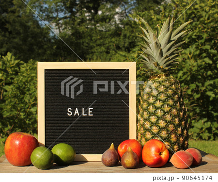 Fresh Pineapple outdoors with Apricots, Peaches and figs. sale sign garden in background Fresh Pineapple outdoors with Apricots, Peaches and figs. sale sign garden in background 90645174