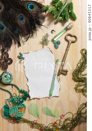 Vintage Burned Paper and Antique Key Surrounded By Green Jewelry and Peacock Feathers 90645317