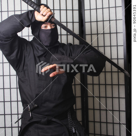 Asian Man Wearing Ninja Costume and holding Ninja Weapons Asian Man Wearing Ninja Costume and holding Ninja Weapons 90645391