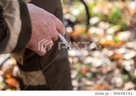 A smoking cigarette in a man's hand. Bad habit. The concept of the dangers of smoking and tobacco consumption with copy space for text 90648291