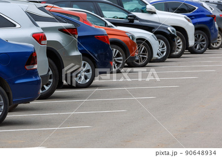 row of different color cars on asphalt parking lot at cloudy summer day 90648934