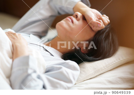 寝苦しそうな中年女性　ベッドで横になる女性　 90649339