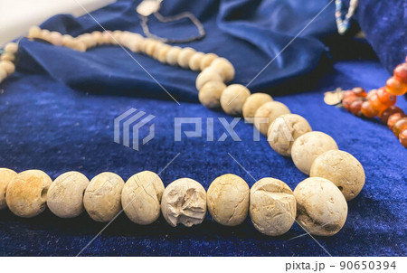 beads made of stones on a blue velvet backing. museum exhibit on a pedestal. jewelry from the ancient world with damage beads made of stones on a blue velvet backing. museum exhibit on a pedestal. jewelry from the ancient world with damage 90650394