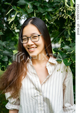 Young Vietnamese woman standing smiling in green fresh tree leaves on sunny day Young Vietnamese woman standing smiling in green fresh tree leaves on sunny day 90650562