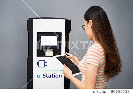 Young Chinese woman using tablet,sets up touchscreen electric car charge station 90650582