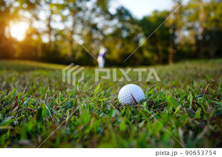 Golf ball is on a green lawn in a beautiful golf course with morning sunshine. Golf ball is on a green lawn in a beautiful golf course with morning sunshine. 90653754