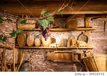 Vintage winery cellar with straw baskets and branch of grapes 90656558
