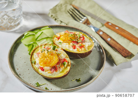 Avocado baked with egg, ham, tomatoes and cheese. Keto lunch recipe. After baking Avocado baked with egg, ham, tomatoes and cheese. Keto lunch recipe. After baking 90658707