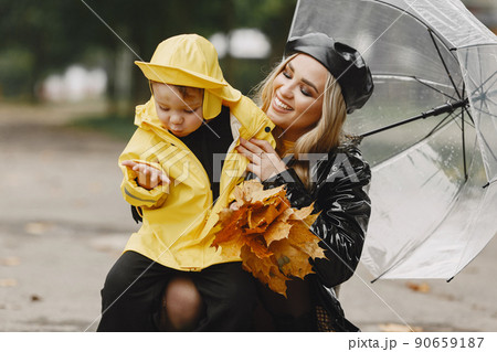 Family in a rainy park. Kids in a raincoats. Mother with child. Woman in a black coat. Family in a rainy park. Kids in a raincoats. Mother with child. Woman in a black coat. 90659187