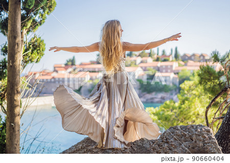 Woman tourist on background of beautiful view of the island of St. Stephen, Sveti Stefan on the Budva Riviera, Budva, Montenegro. Travel to Montenegro concept Woman tourist on background of beautiful view of the island of St. Stephen, Sveti Stefan on the Budva Riviera, Budva, Montenegro. Travel to Montenegro concept 90660404