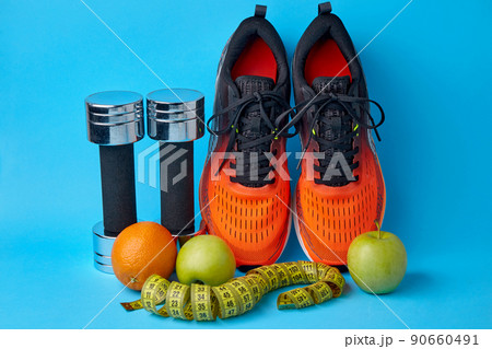 Orange sneakers, dumbbells, measuring tape and fruits apples and oranges 90660491